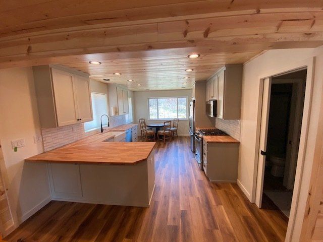 Kitchen with light gray cabinets, wood countertops, and hardwood floors.