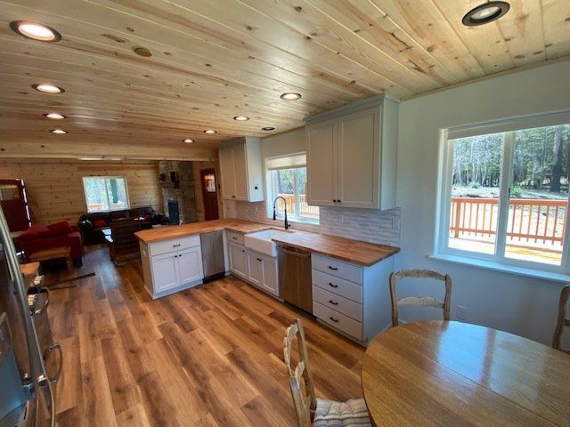 Bright kitchen with wood cabinets, countertops, and flooring. Light-colored walls, ceiling, and large window.