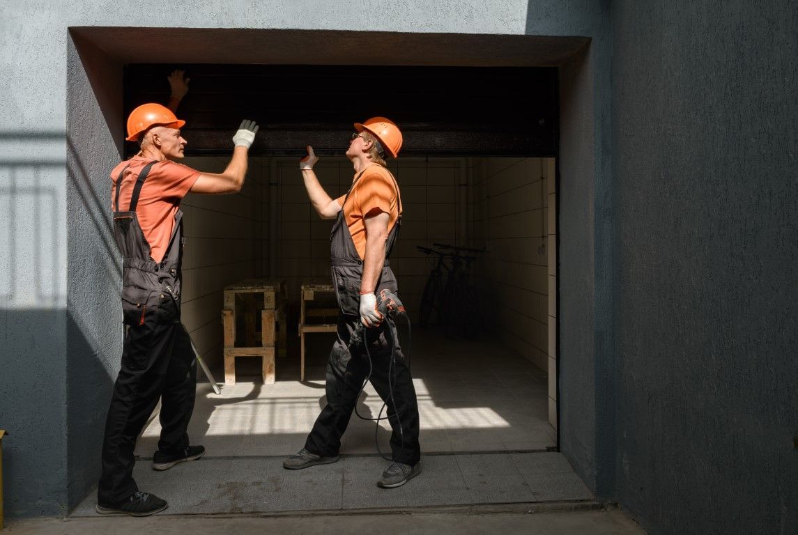 Two technicians installing a garage door opener.