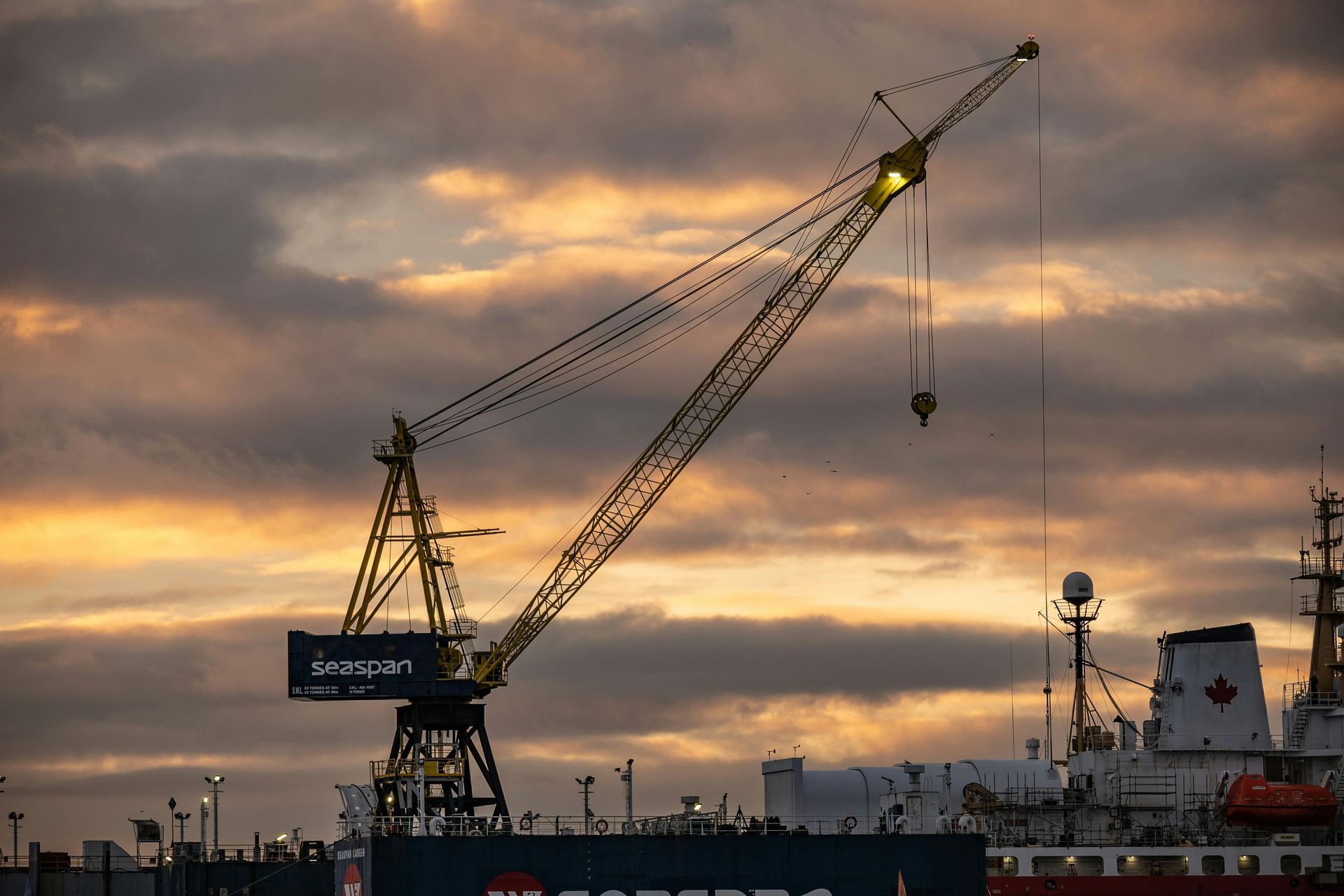 Crane at a shipyard against a sunset sky.