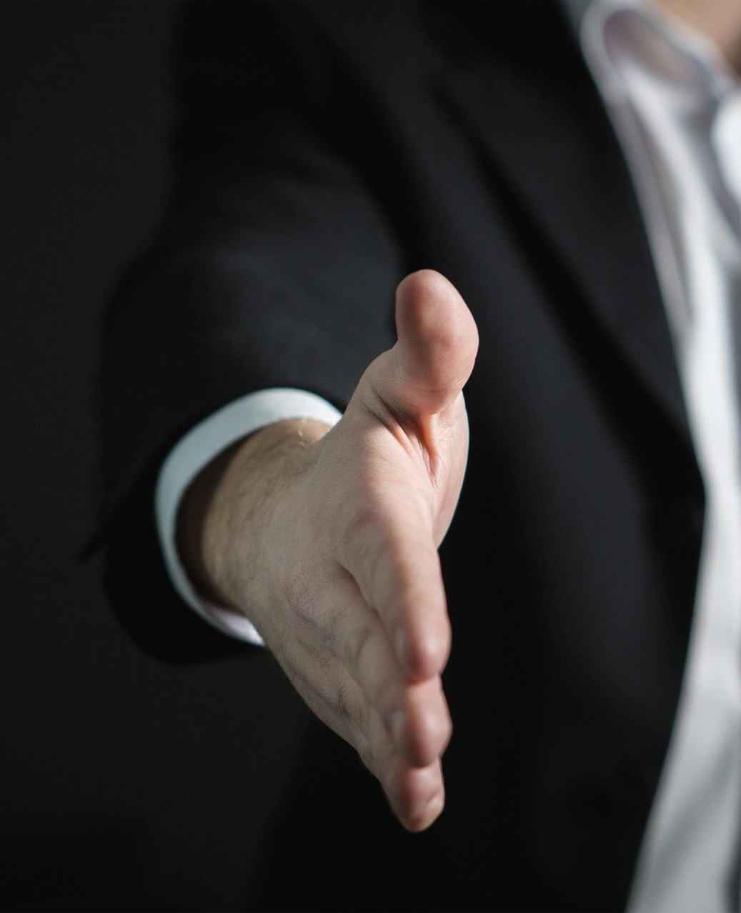 Man in suit extends hand for a handshake.