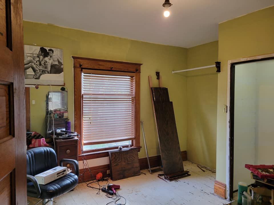 A room with a chair and a window with blinds.