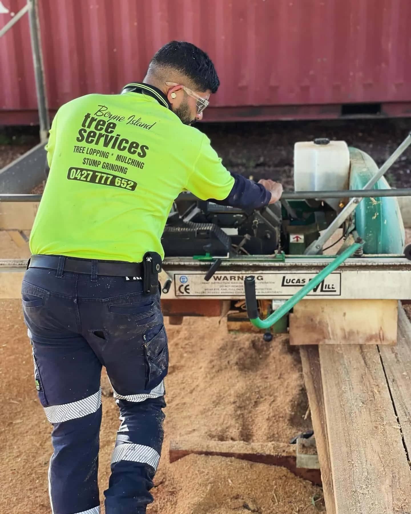 A Man in A Yellow Shirt Is Working on A Machine — Boyne Island Tree Services in Boyne Island, QLD
