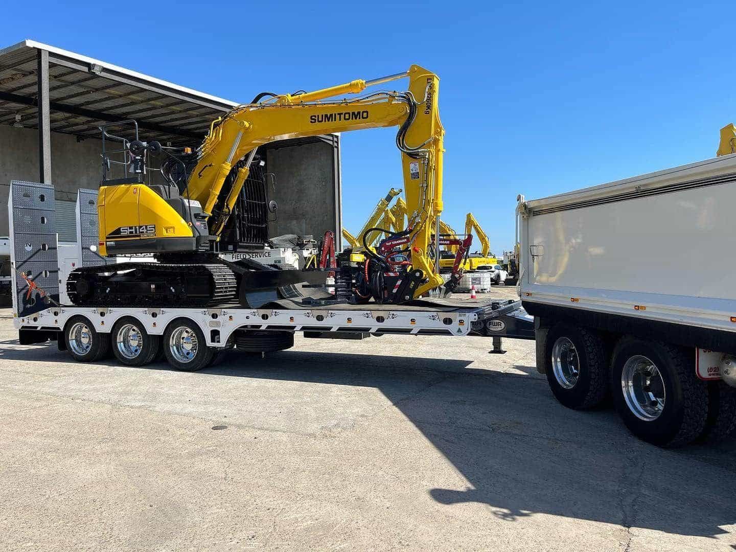 A Yellow Excavator Is Sitting on Top of A White Trailer — Boyne Island Tree Services in Boyne Island, QLD