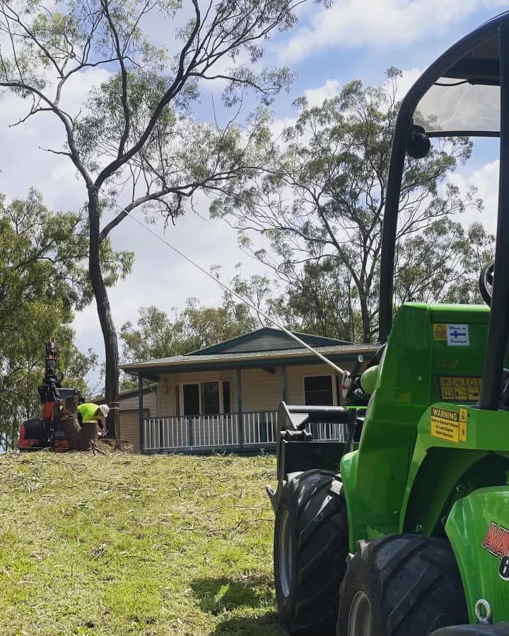 A Green Tractor Is Parked in Front of A House — Boyne Island Tree Services in Boyne Island, QLD