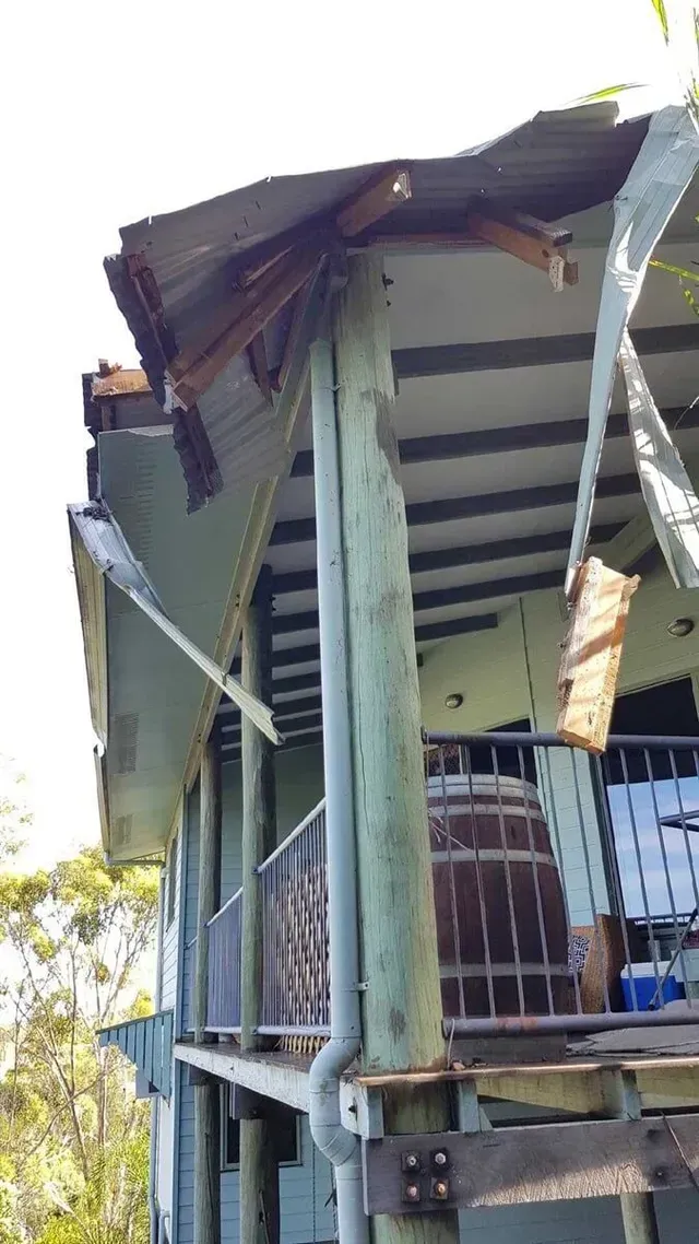 Damage to a two-story building's roof and support structure; metal sheets ripped, wood splintered — Boyne Island Tree Services in Boyne Island, QLD