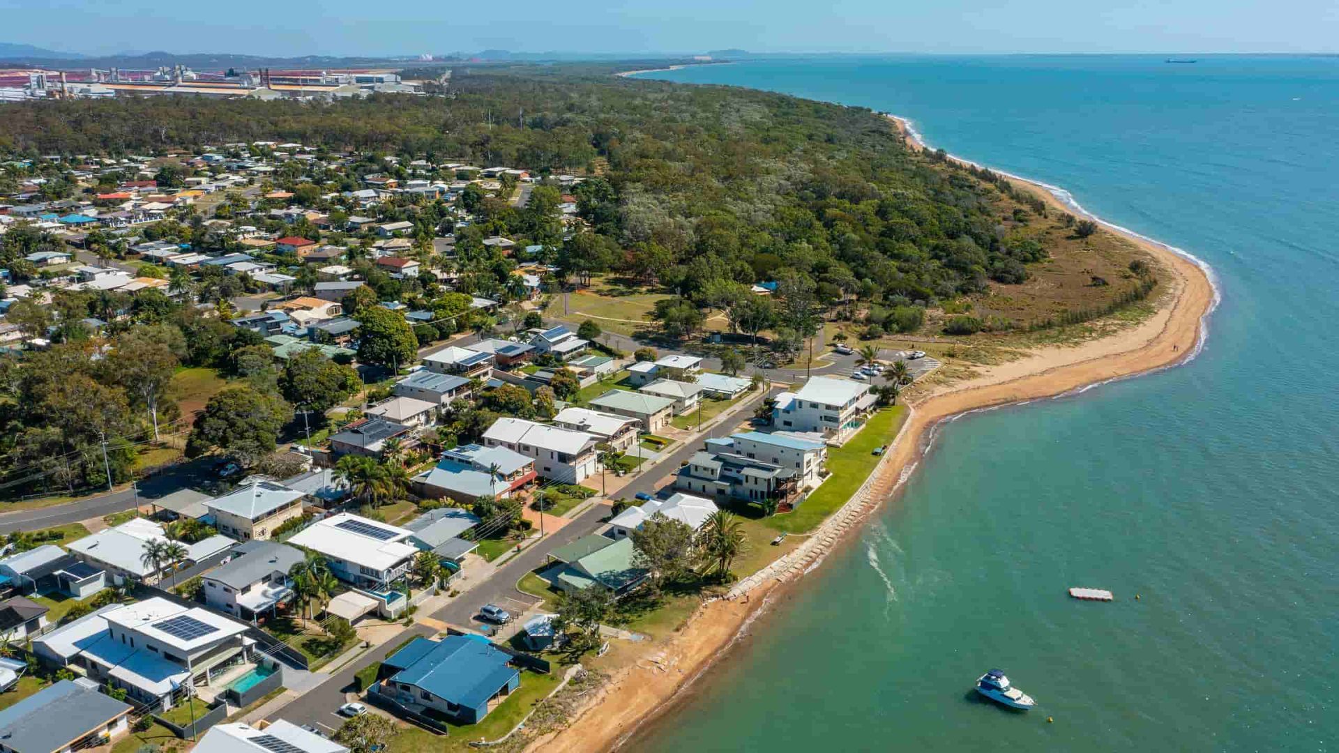 A Yellow Stump Grinder Is Cutting a Tree Stump in A Lush Green Field — Boyne Island Tree Services in Boyne Island, QLD