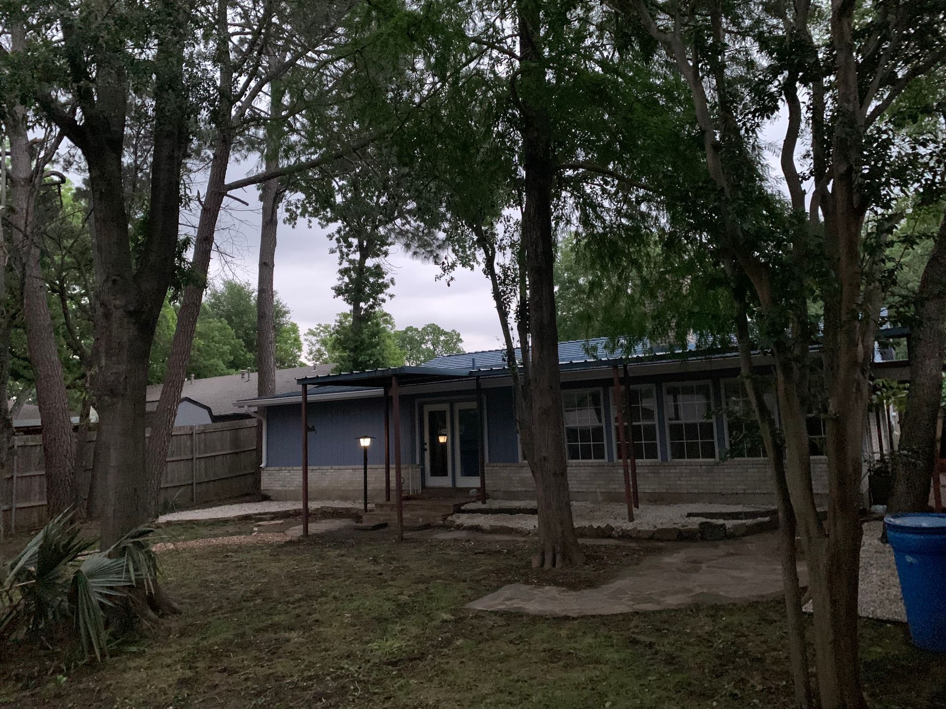 A house with a blue roof is surrounded by trees.