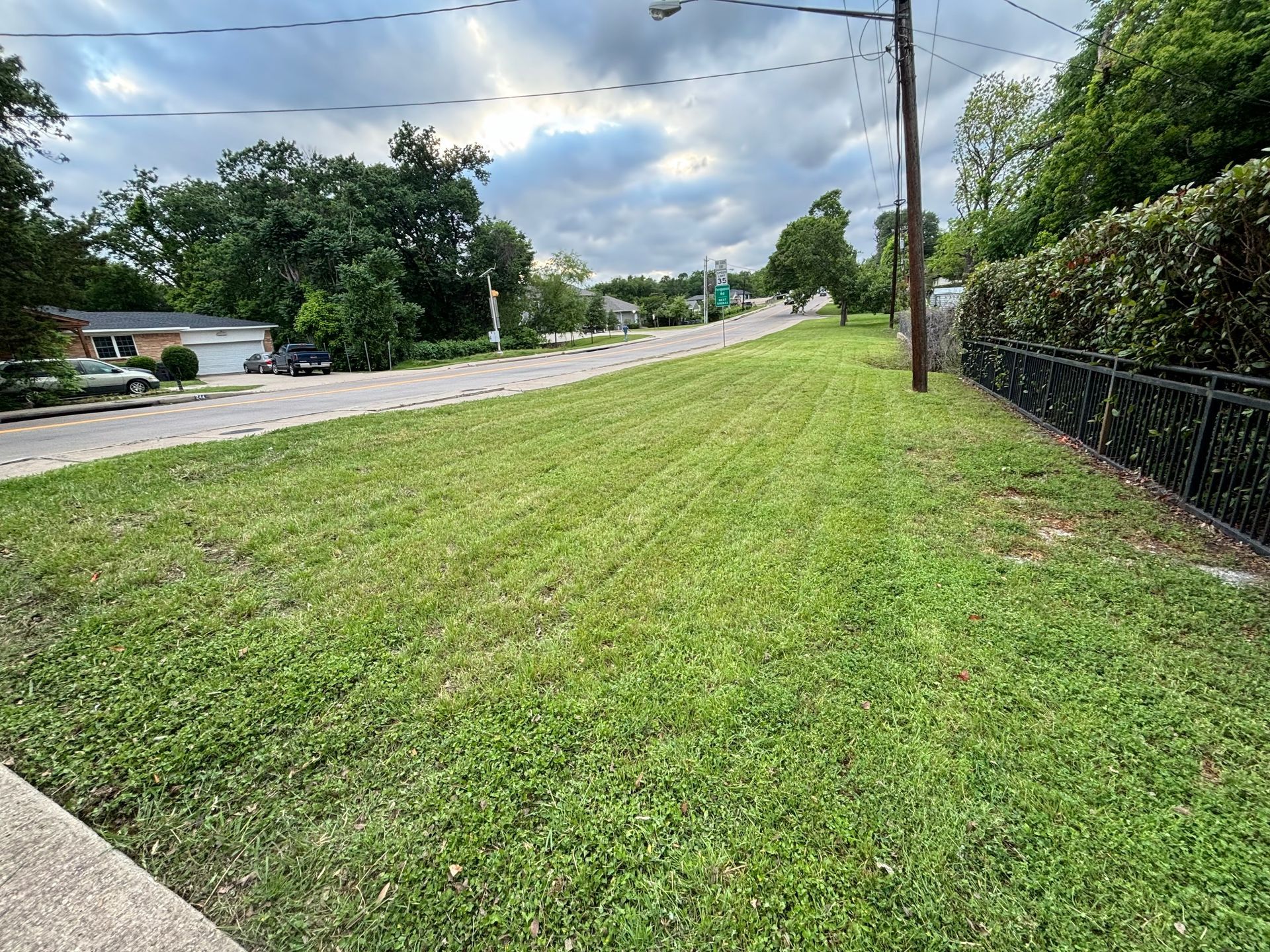 A lush green lawn is along the side of a road.