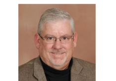 A man wearing glasses and a suit is smiling for the camera