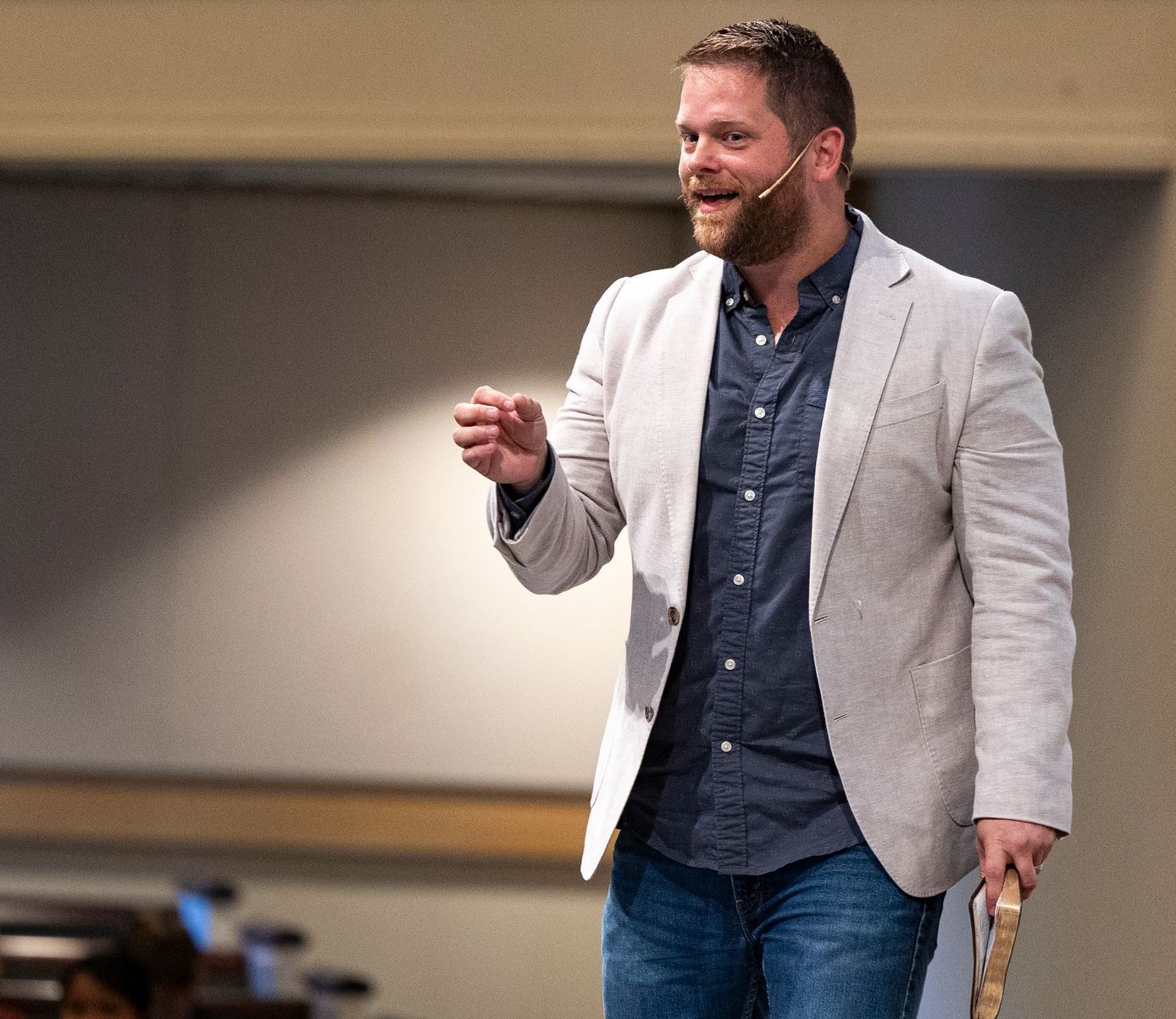 A man wearing a jacket and a microphone is giving a presentation