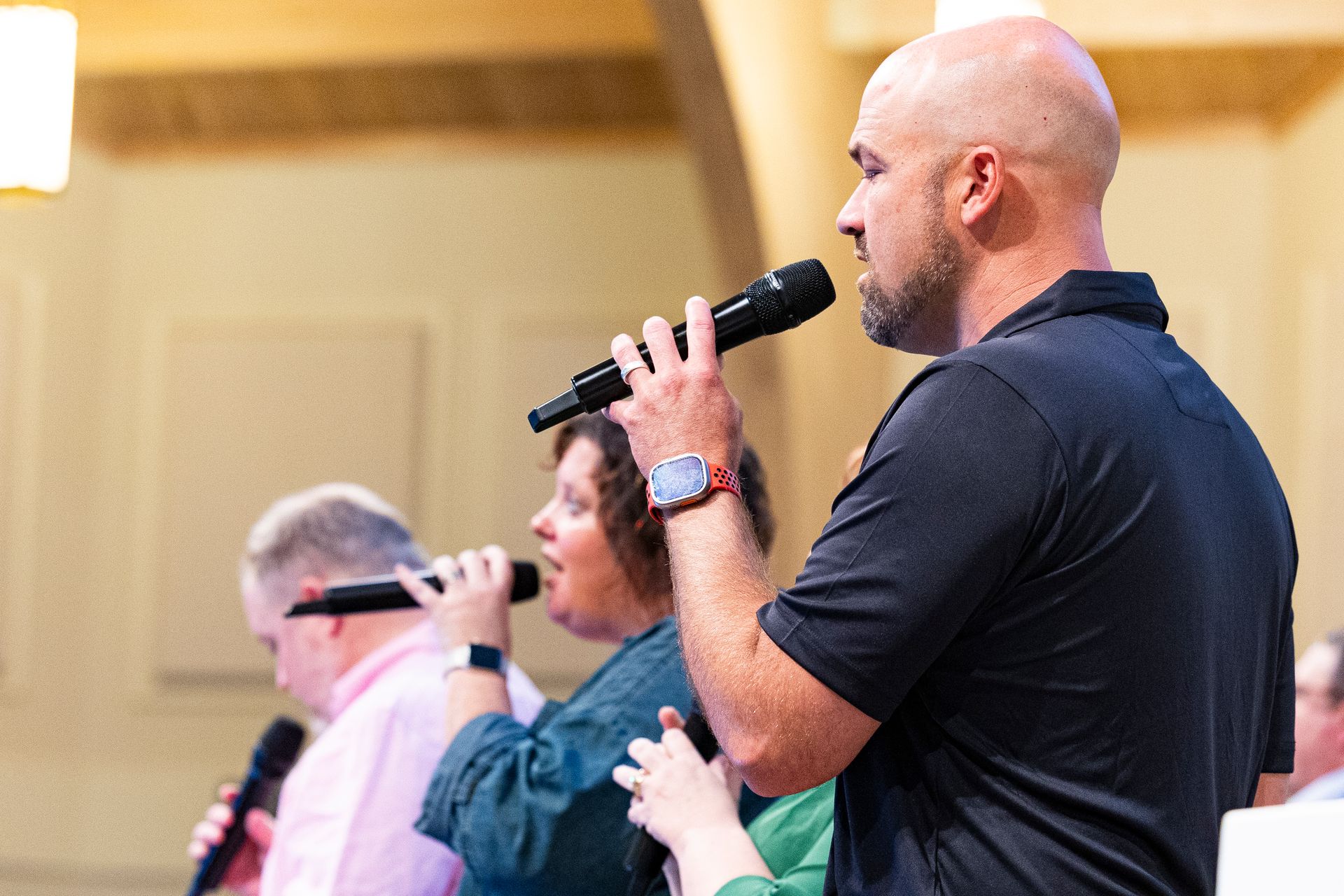 A man is holding a microphone in front of a group of people.