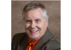 A man in a suit and tie is smiling for the camera