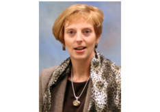 A woman wearing a scarf and a necklace looks at the camera