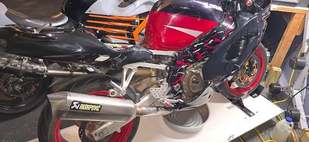 Black and red sport motorcycle parked indoors on a stand, with another bike partly visible nearby