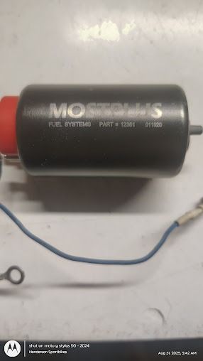 Black cylindrical motor with red end cap and blue wire on a white surface