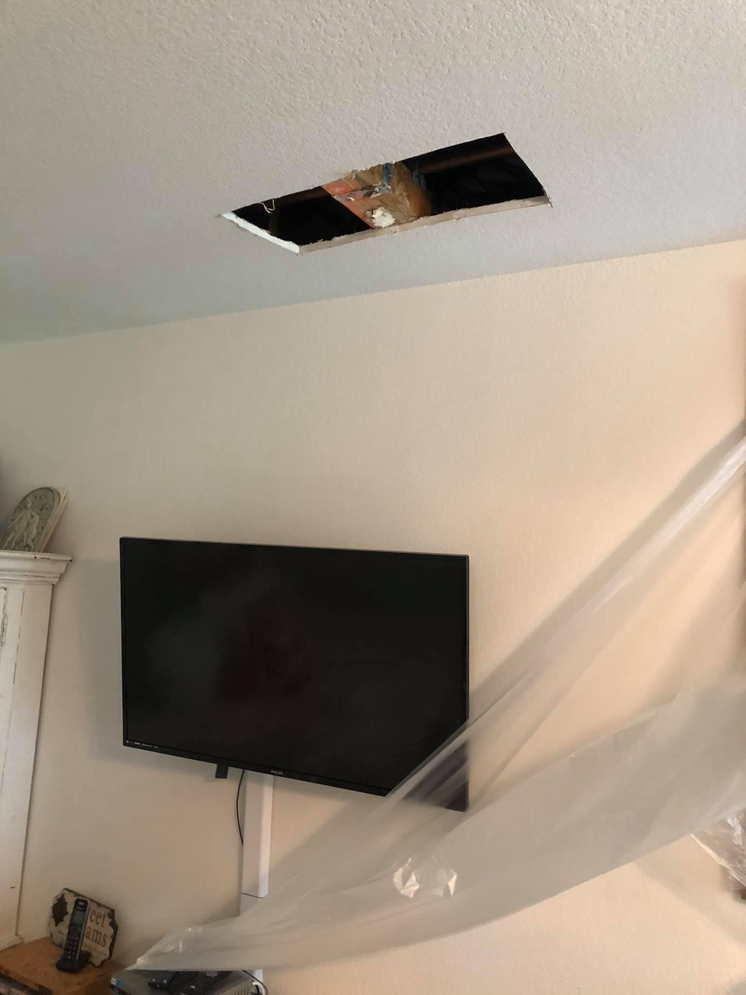 A flat screen tv is hanging from the ceiling in a living room.