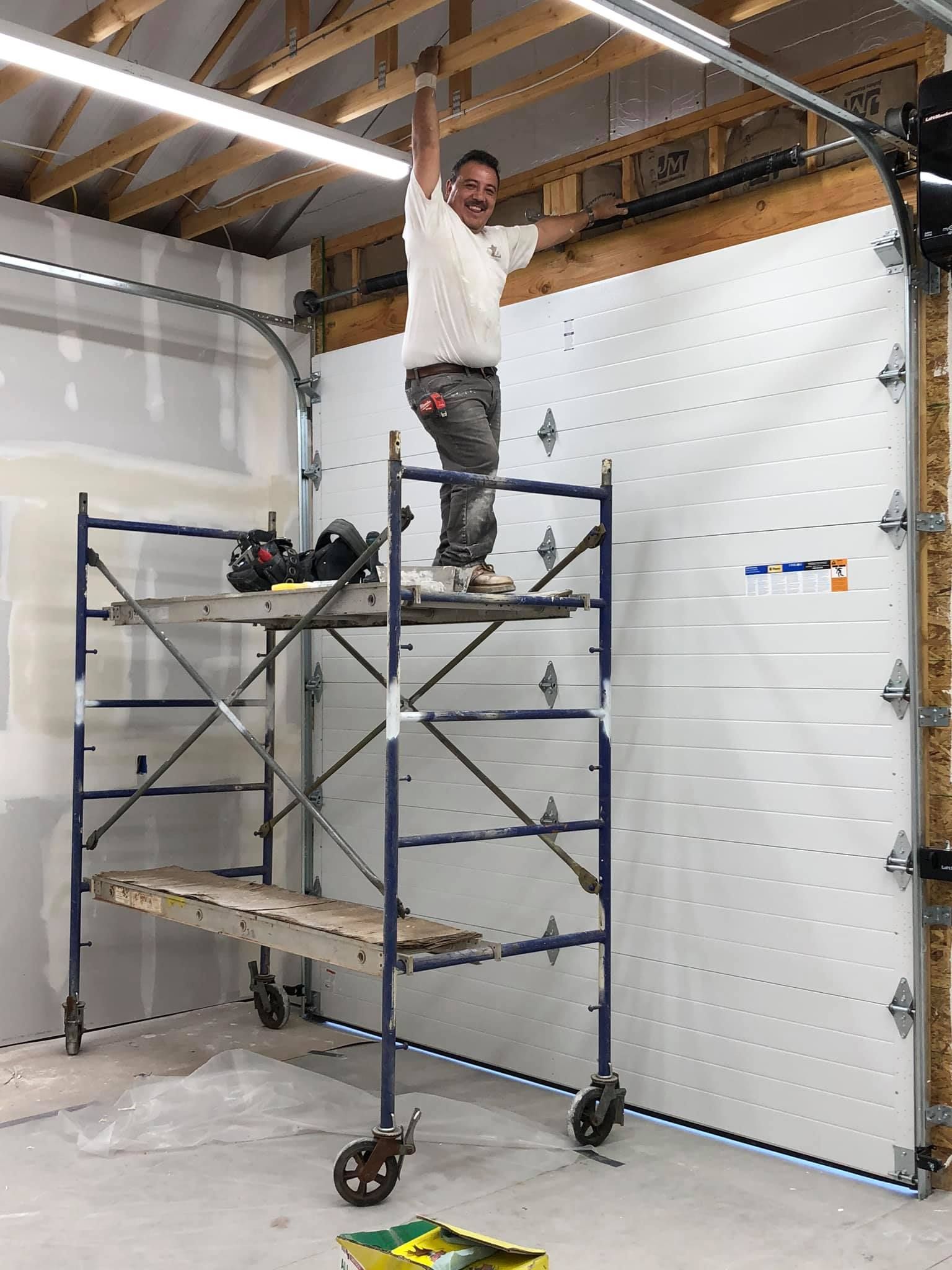 A man is standing on a scaffolding in a garage.