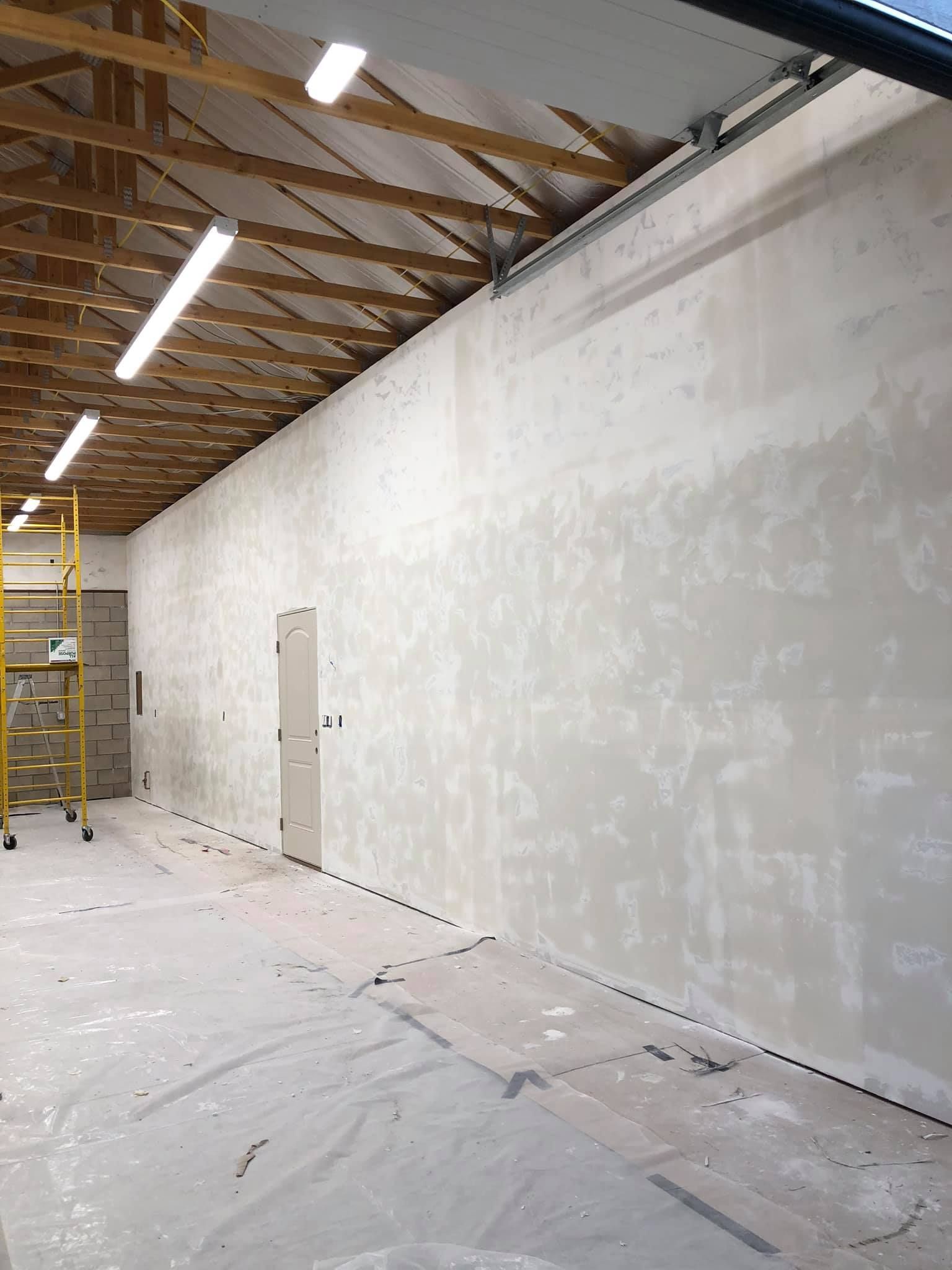 A large room with white walls and a yellow ladder.