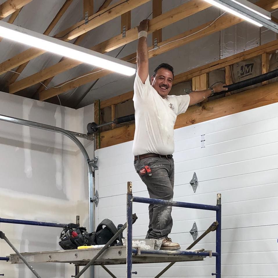 A man is standing on a scaffolding in a garage with his arms in the air.