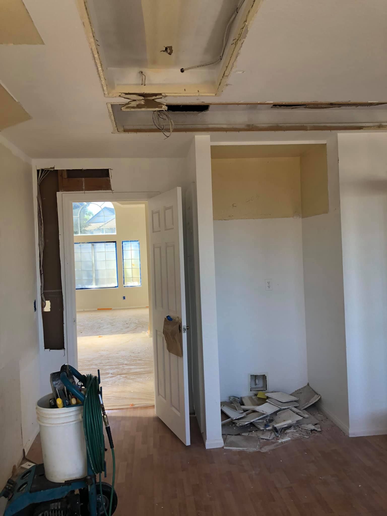 An empty room with a door open and a bucket on the floor.