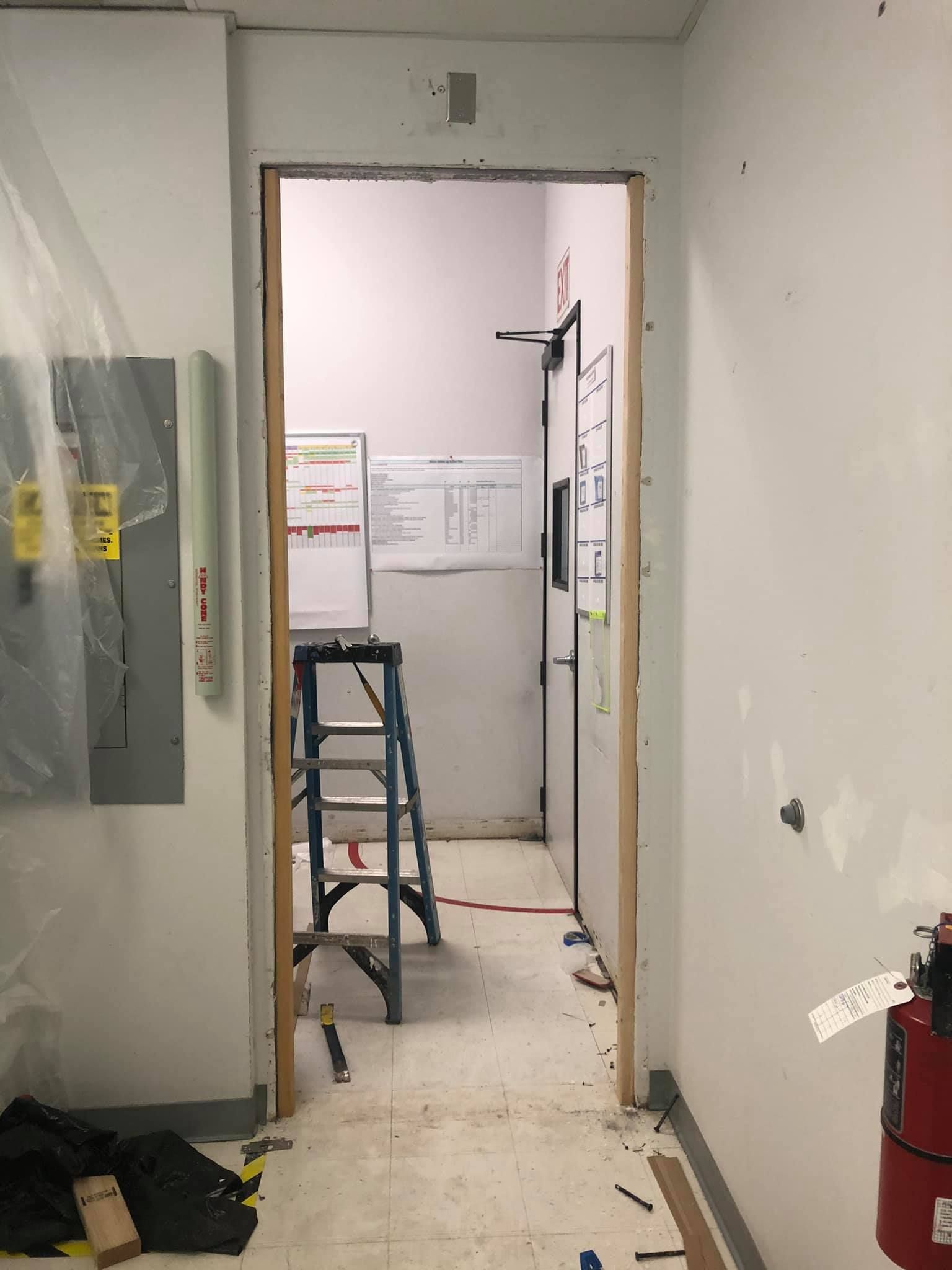 A hallway with a ladder and a fire extinguisher in it.