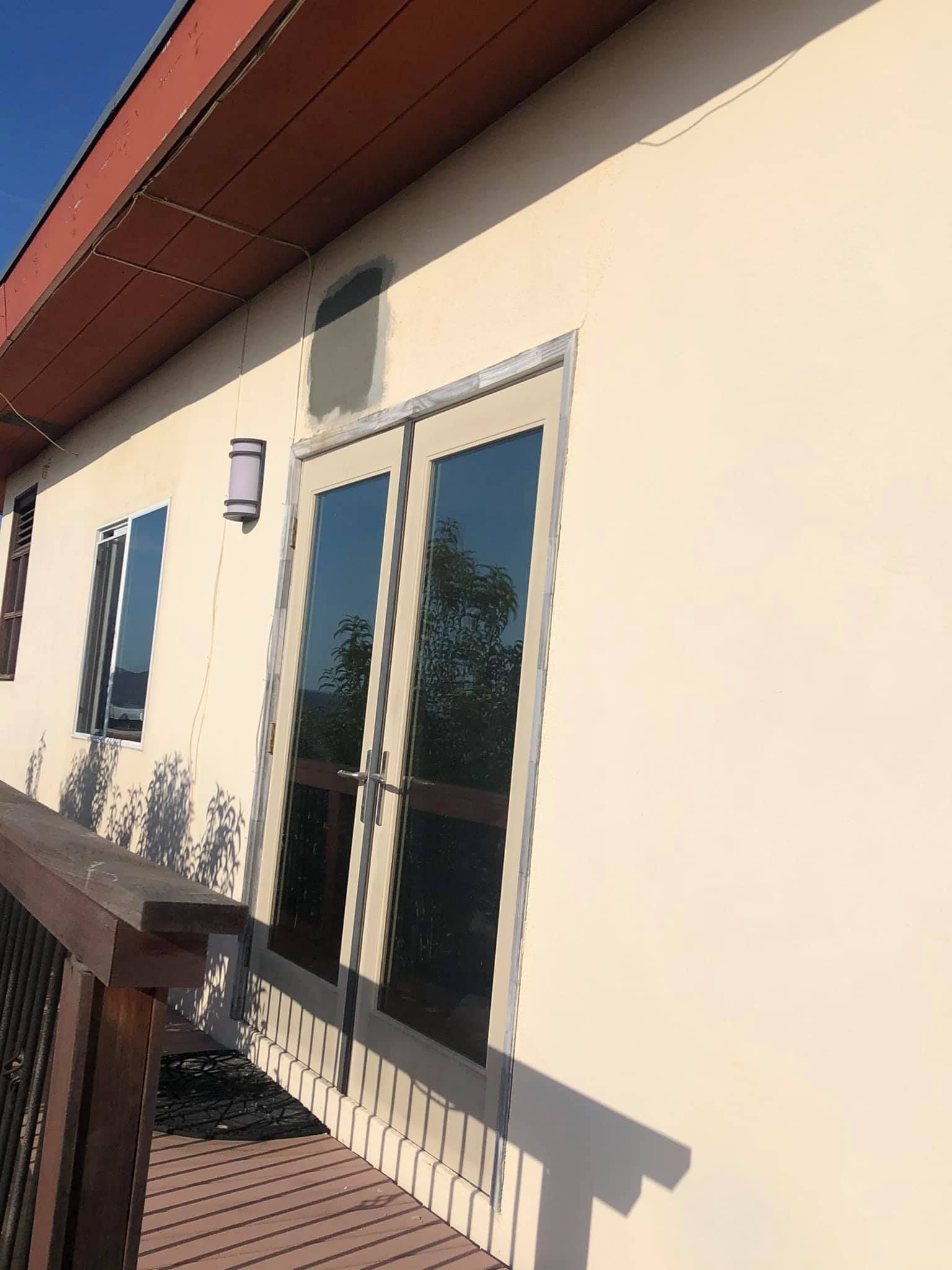 A white building with sliding glass doors and a wooden deck