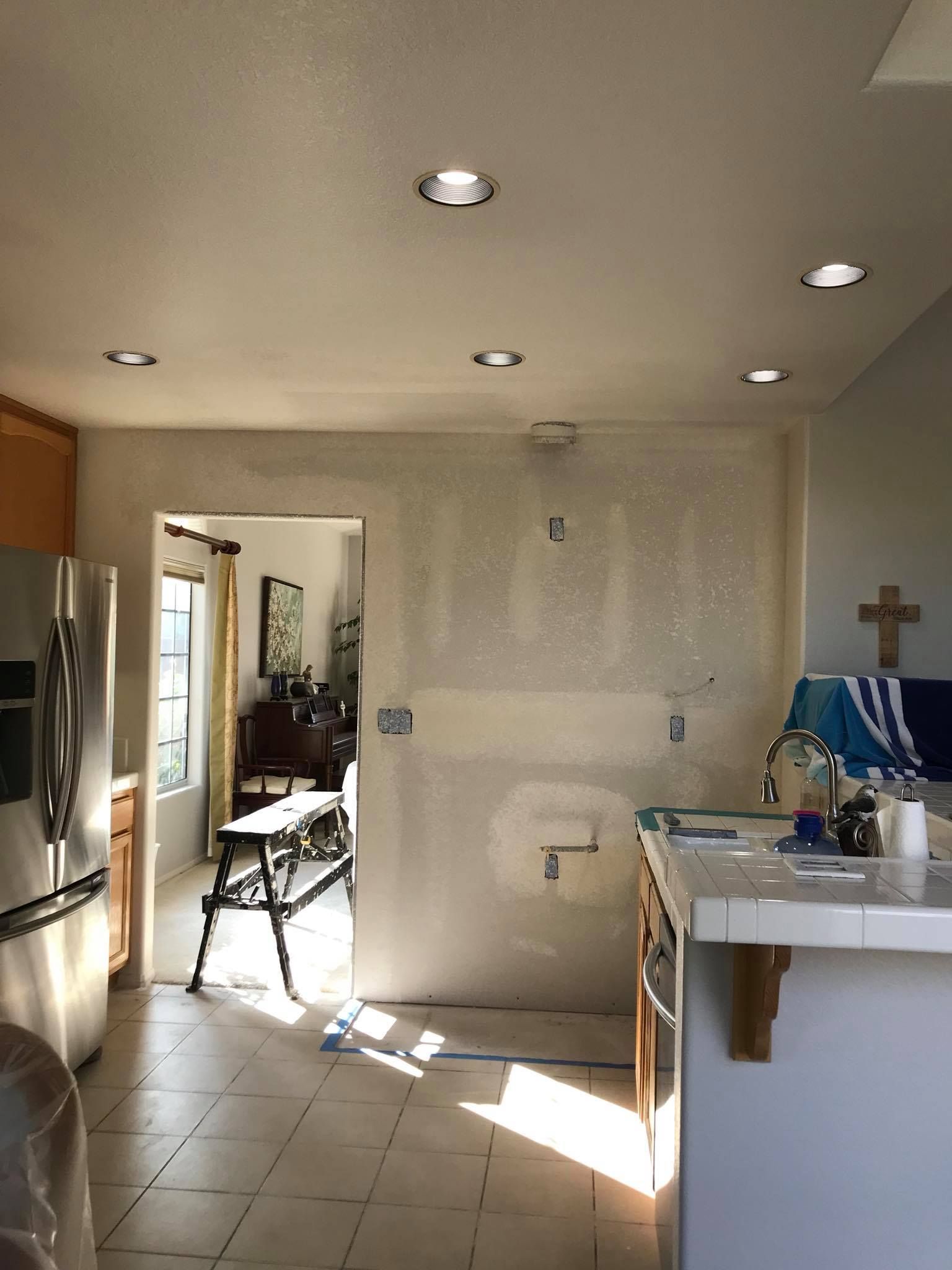 A kitchen with a refrigerator , sink , and a cross on the wall.