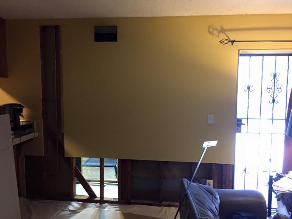 A living room with a couch and a window with a hole in the wall.