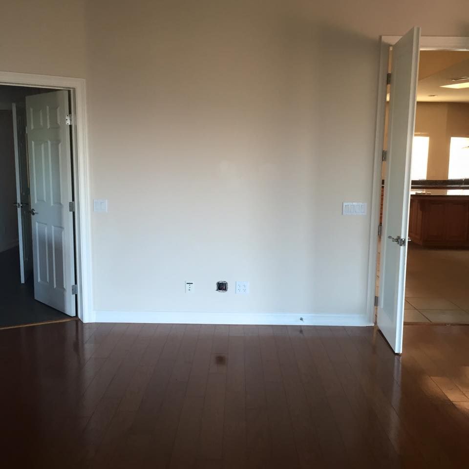 An empty room with hardwood floors and a white door