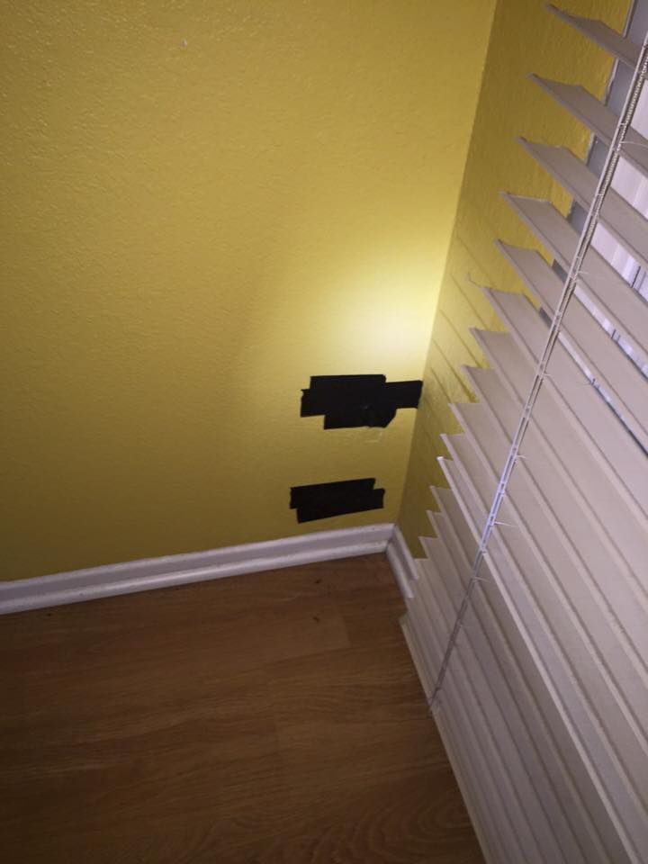 A corner of a room with blinds and a yellow wall.