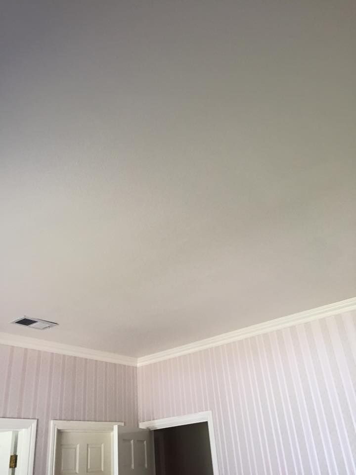 A bedroom with a white ceiling and striped wallpaper.