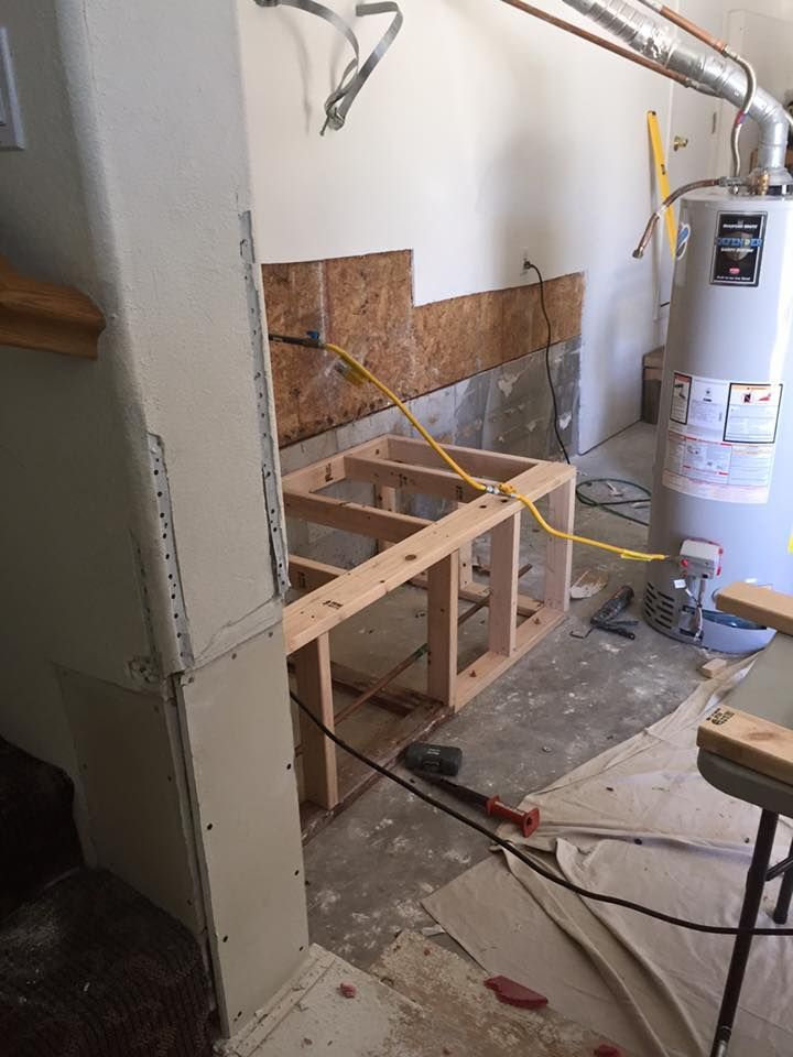A room under construction with a water heater and a wooden bench.