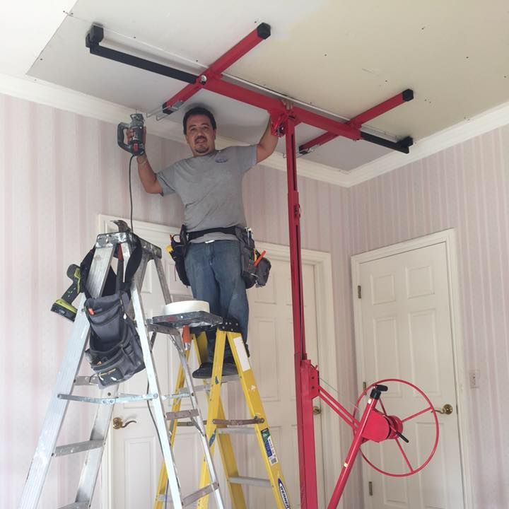 A man standing on a ladder working on a ceiling