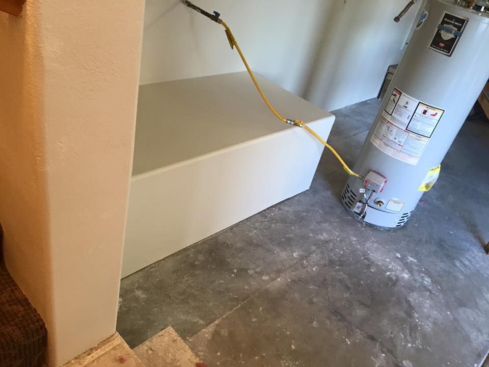 A water heater is sitting on the floor next to a bathtub.