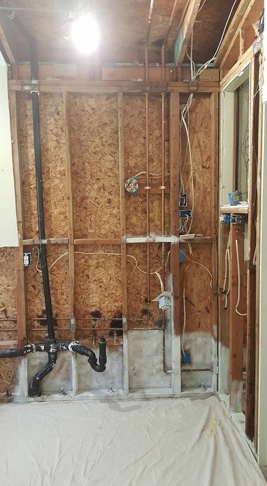 A bathroom under construction with a lot of pipes coming out of the wall.