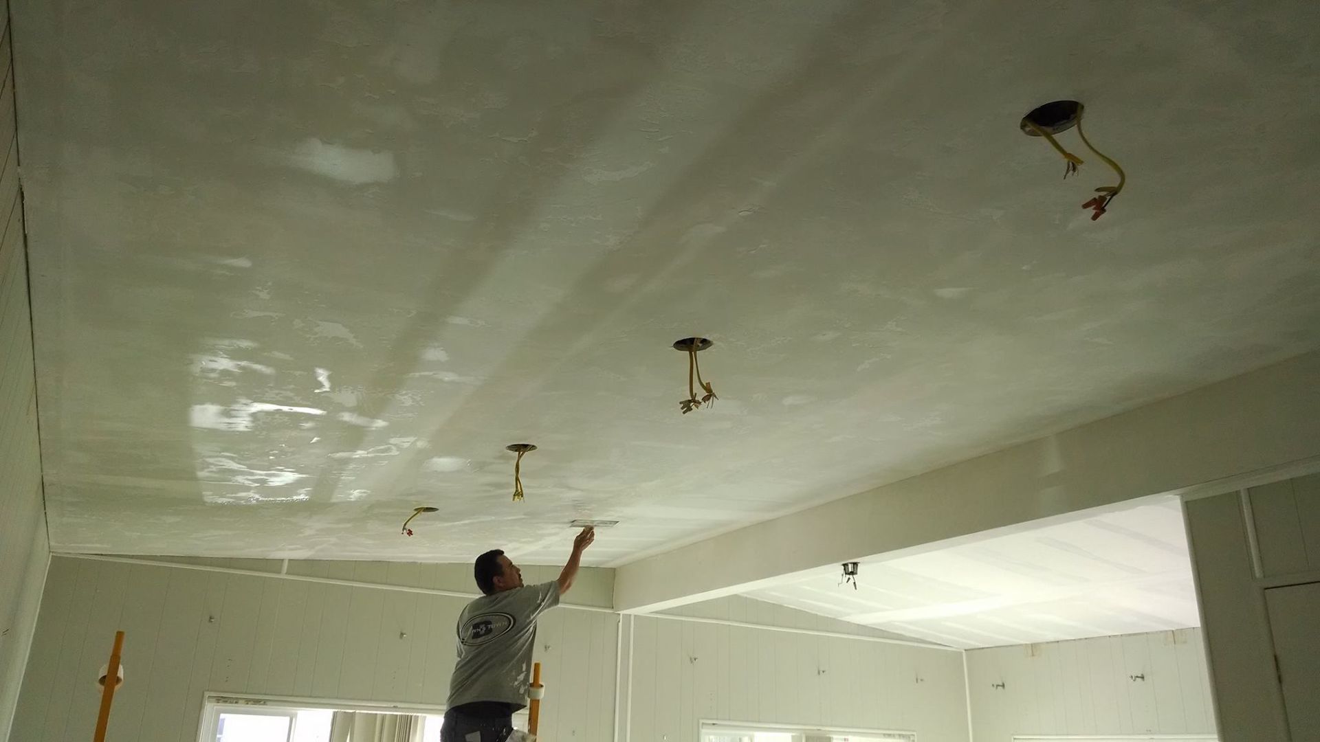 A man is working on a ceiling in a room.