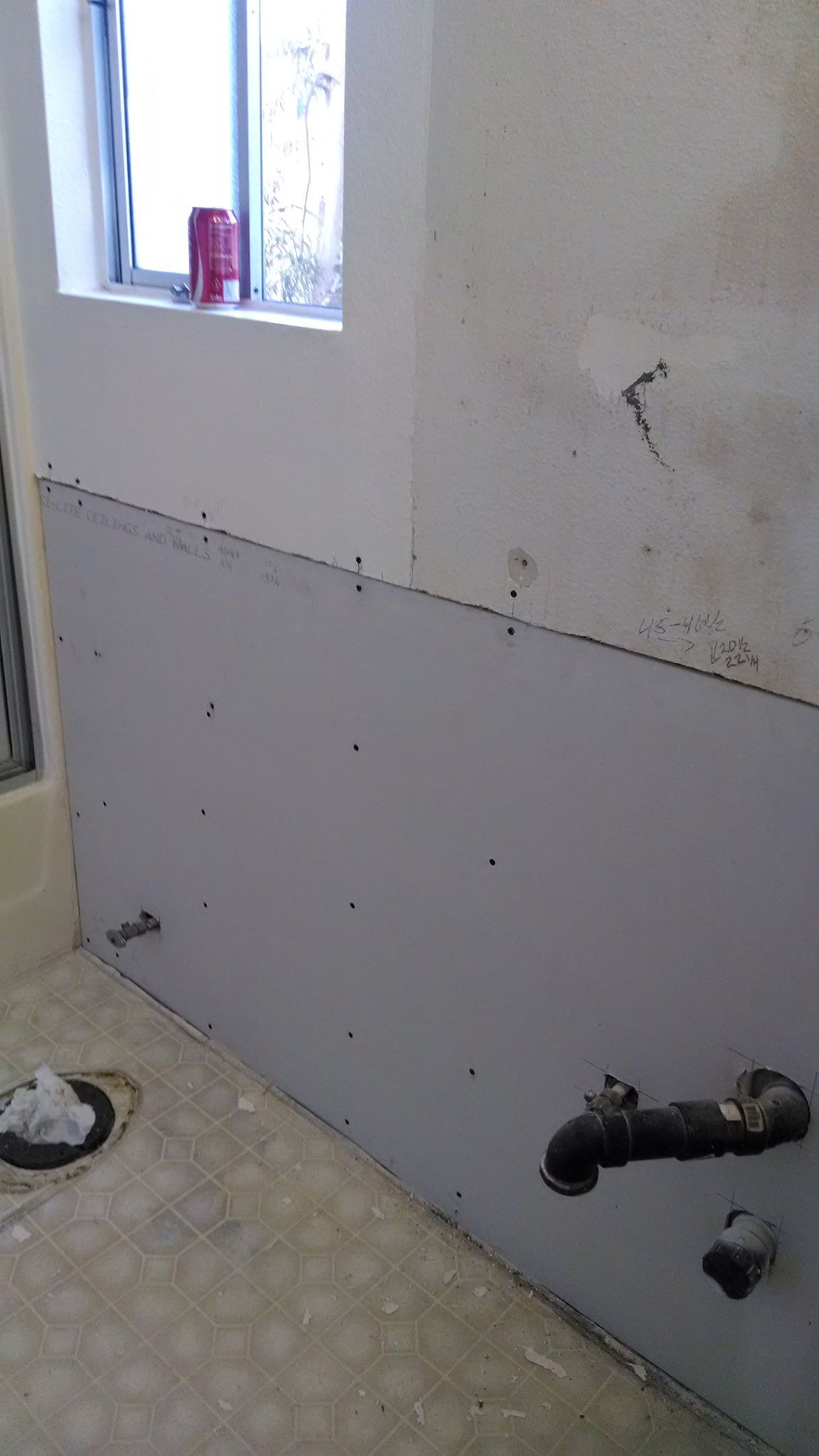 A bathroom with a window and a faucet on the wall.