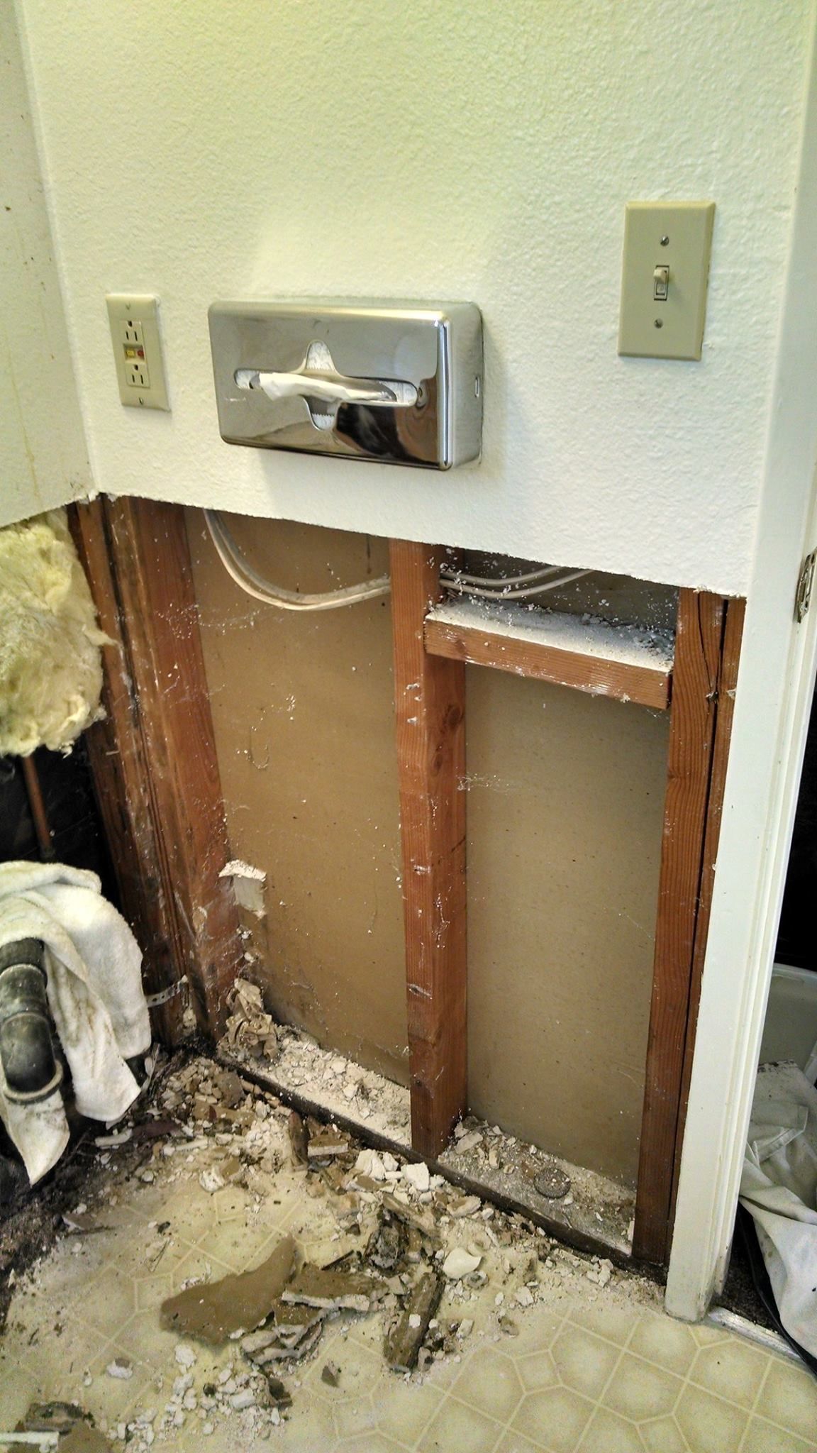 A bathroom with a hole in the wall and a toilet.