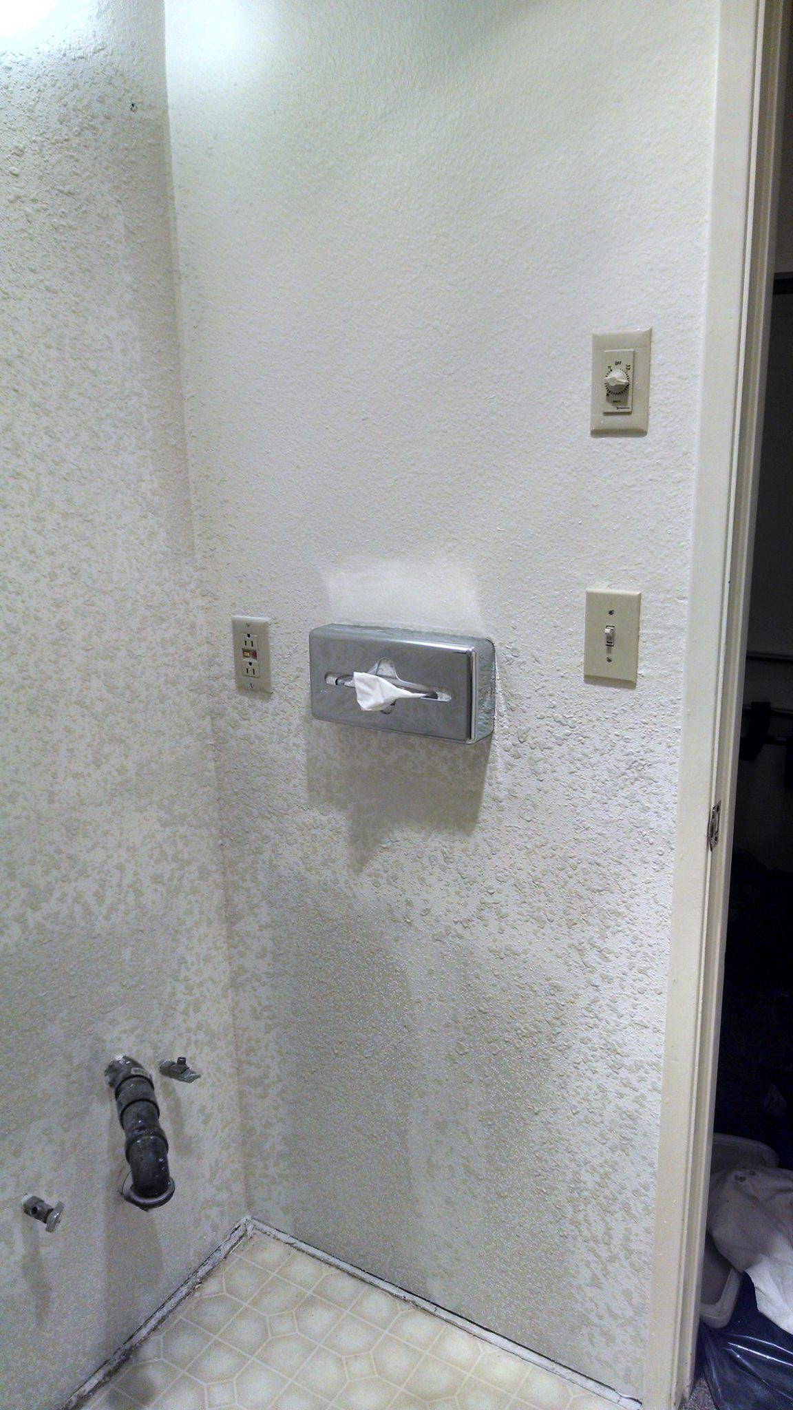 A bathroom with a paper towel dispenser on the wall.