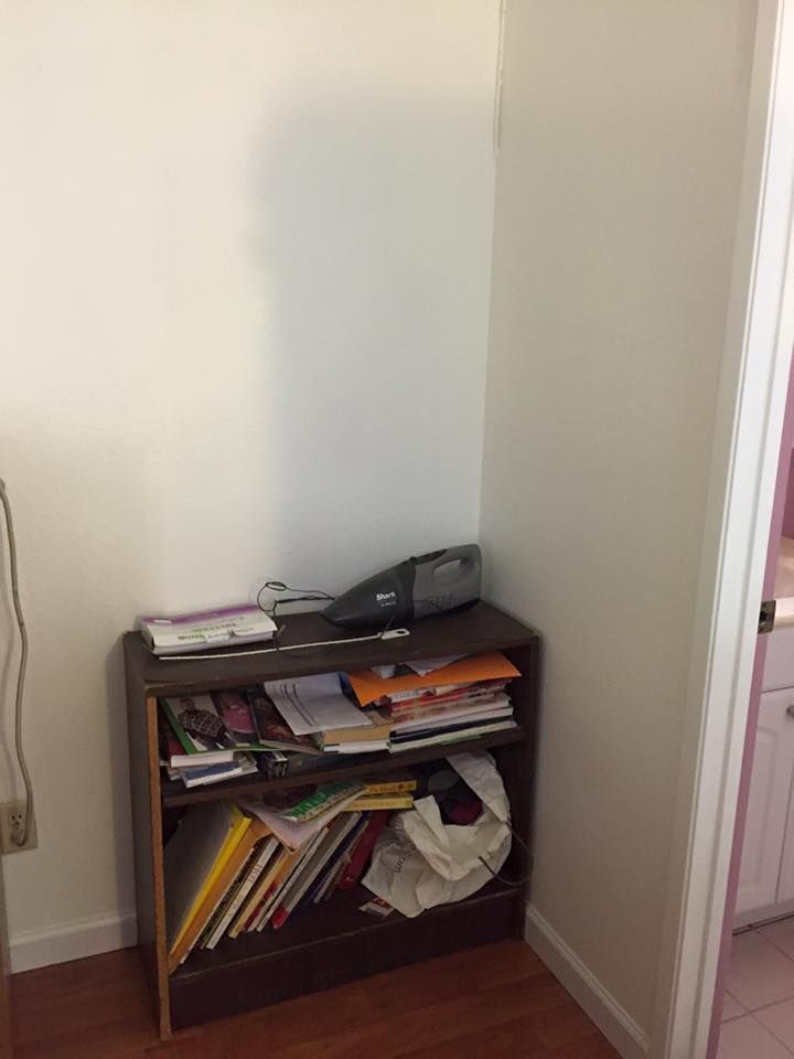 A bookshelf filled with books and papers in a corner of a room.