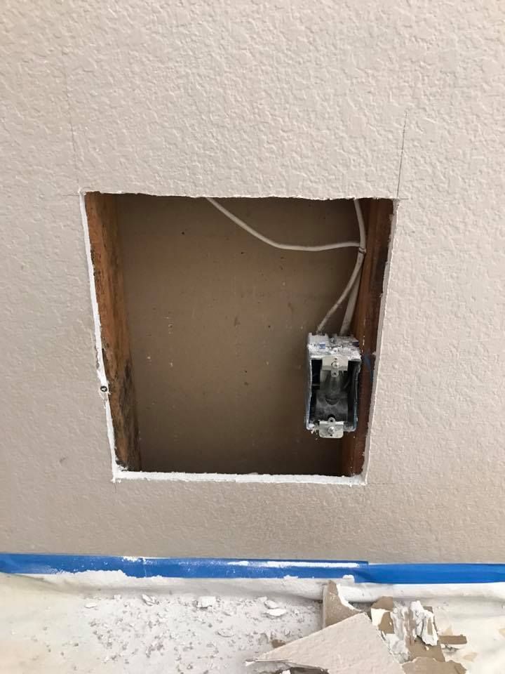 A hole in the wall with wires coming out of it.