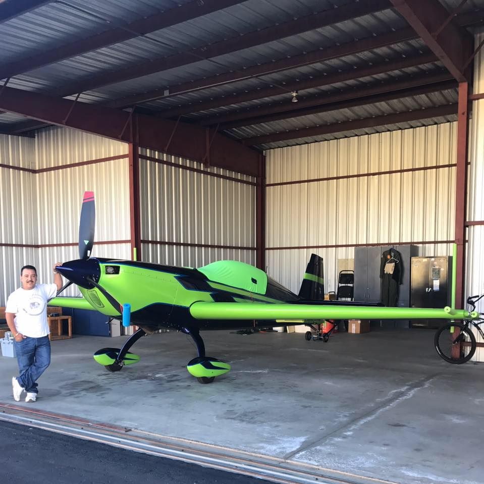 A man is standing in front of a small plane in a hangar.