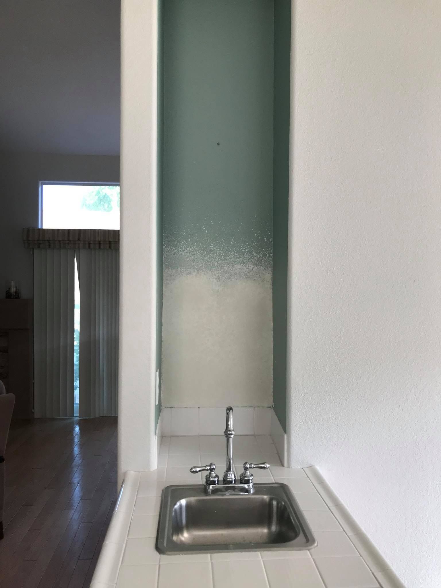 A kitchen sink with a faucet and a window in the background.