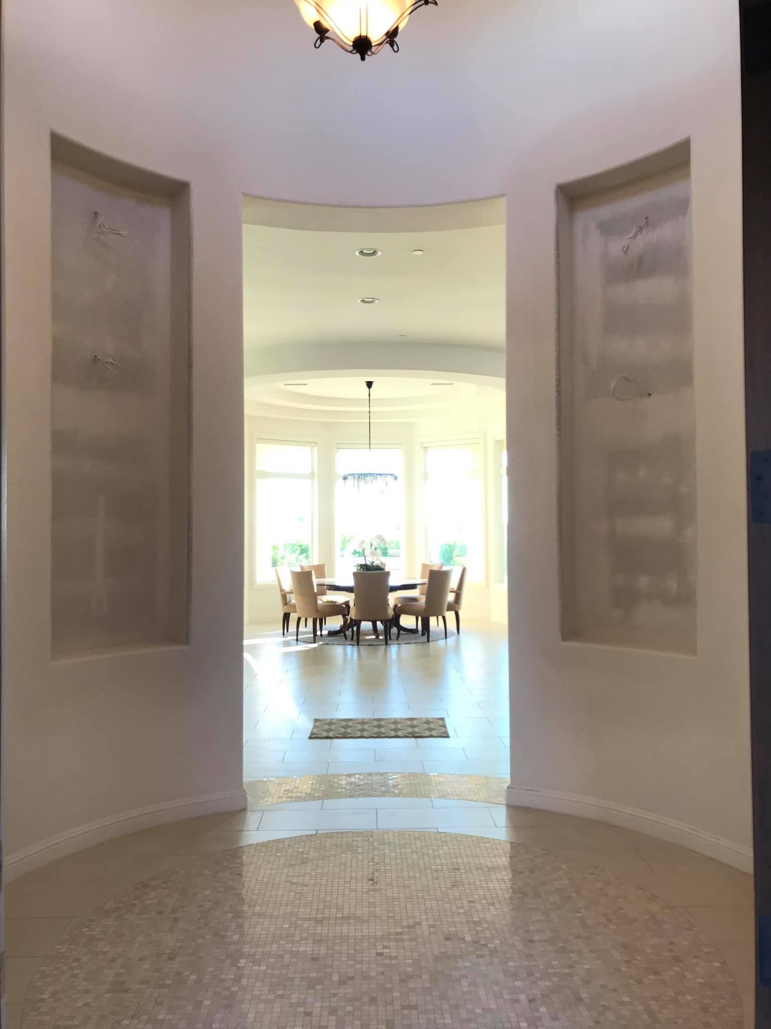 A hallway leading to a dining room with a table and chairs