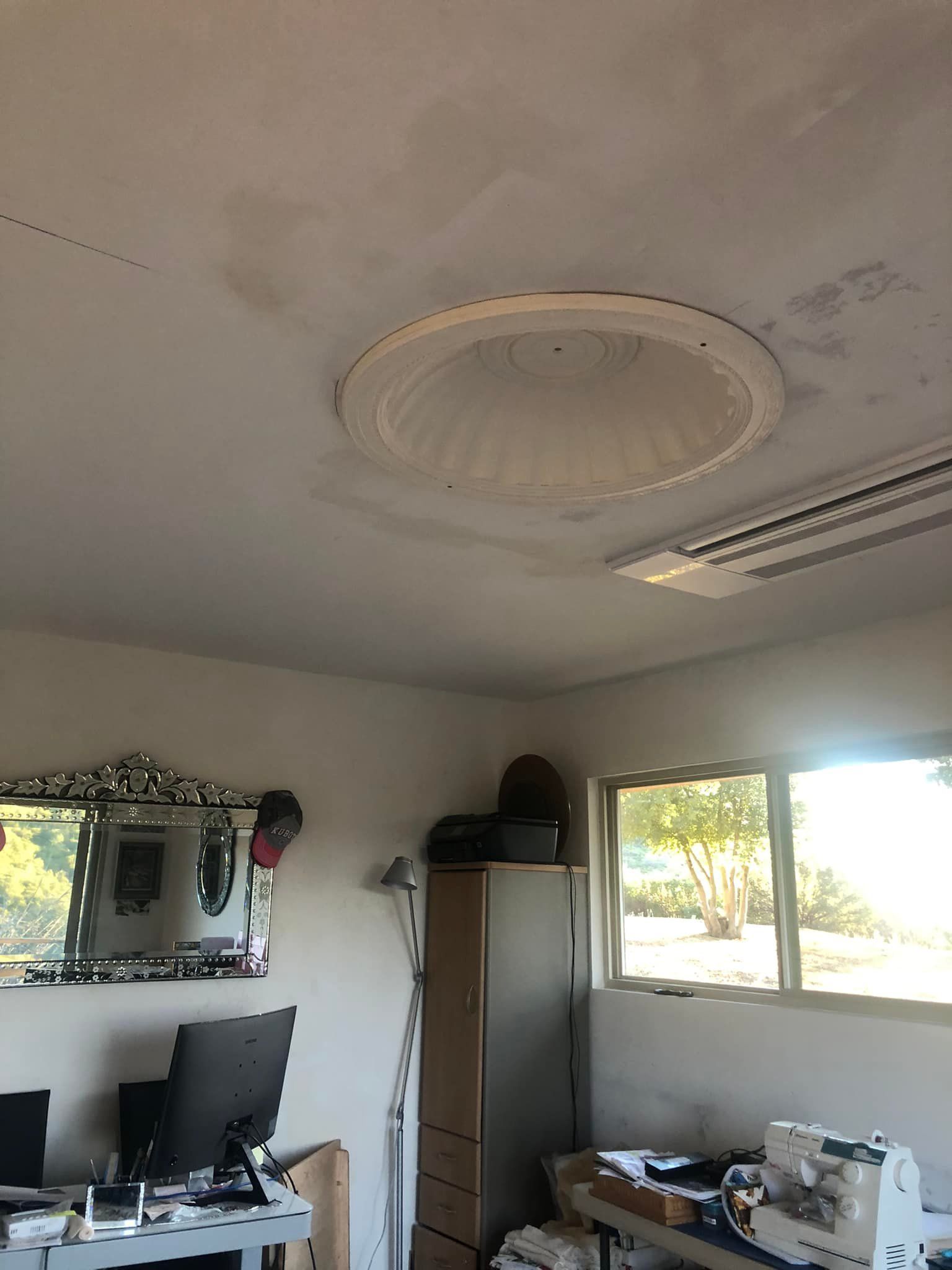 A room with a ceiling light and a mirror on the wall.