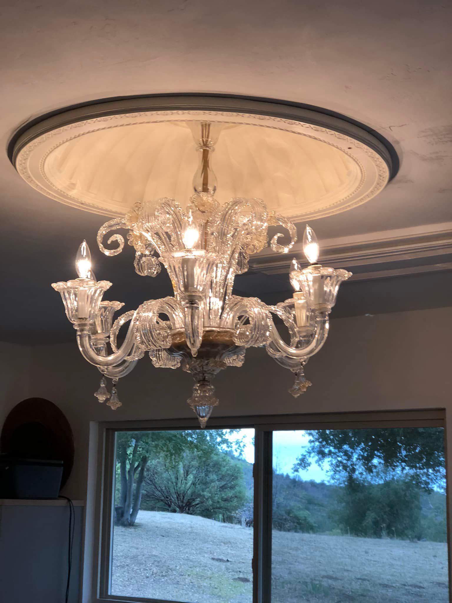 A chandelier is hanging from the ceiling in front of a window.