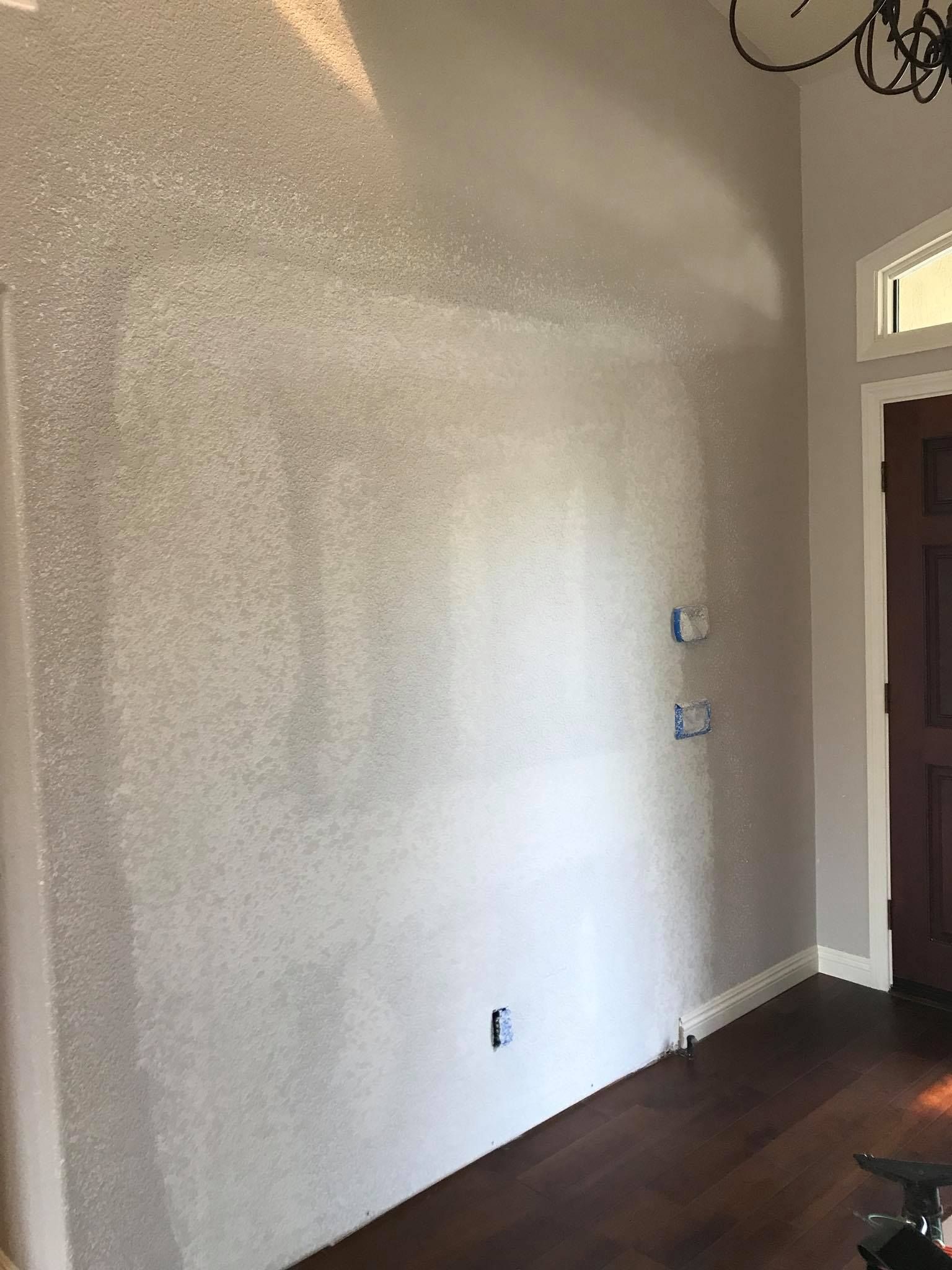 A room with a large white wall and a wooden floor.