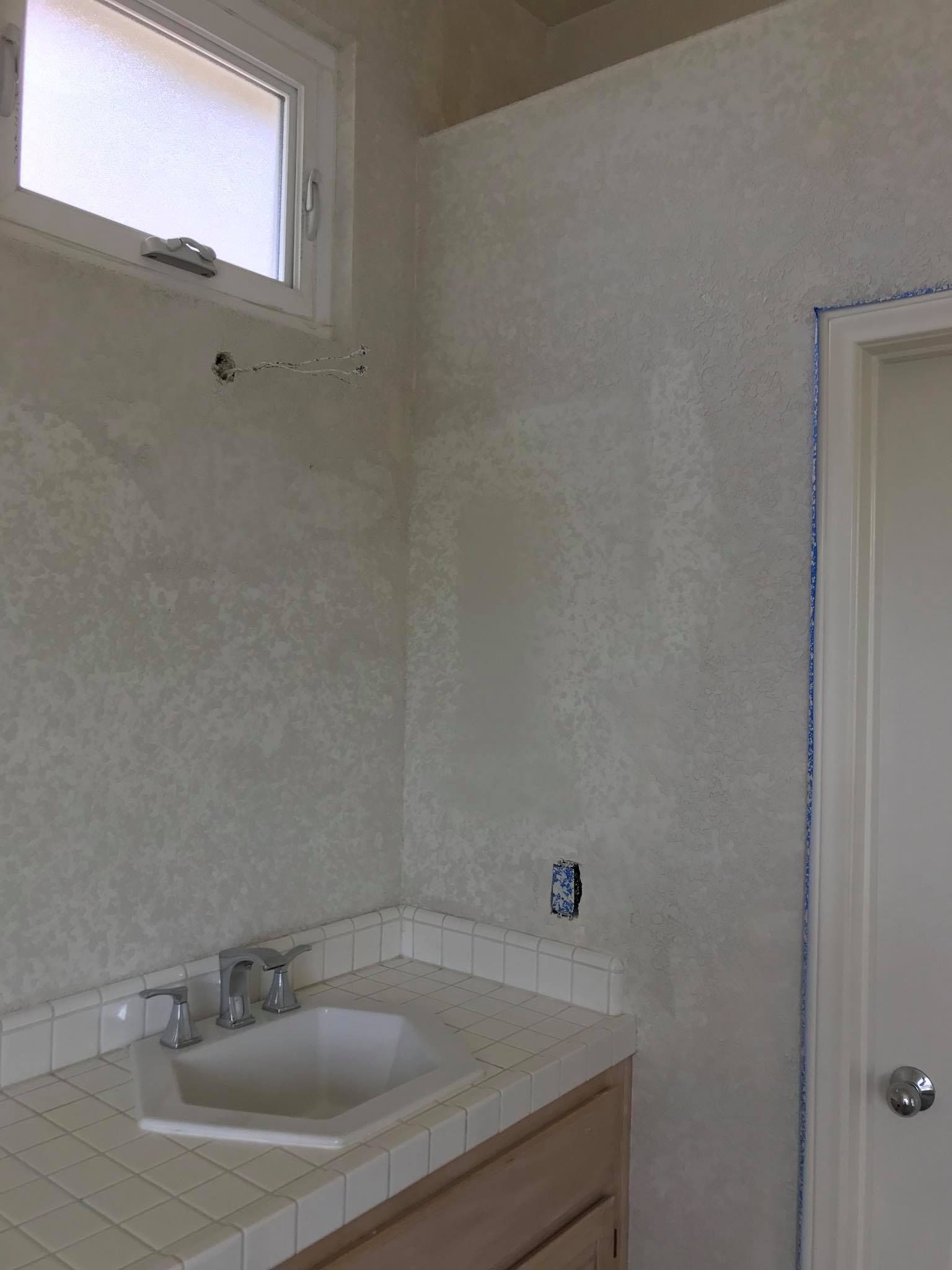 A bathroom with a sink , cabinets , and a window.