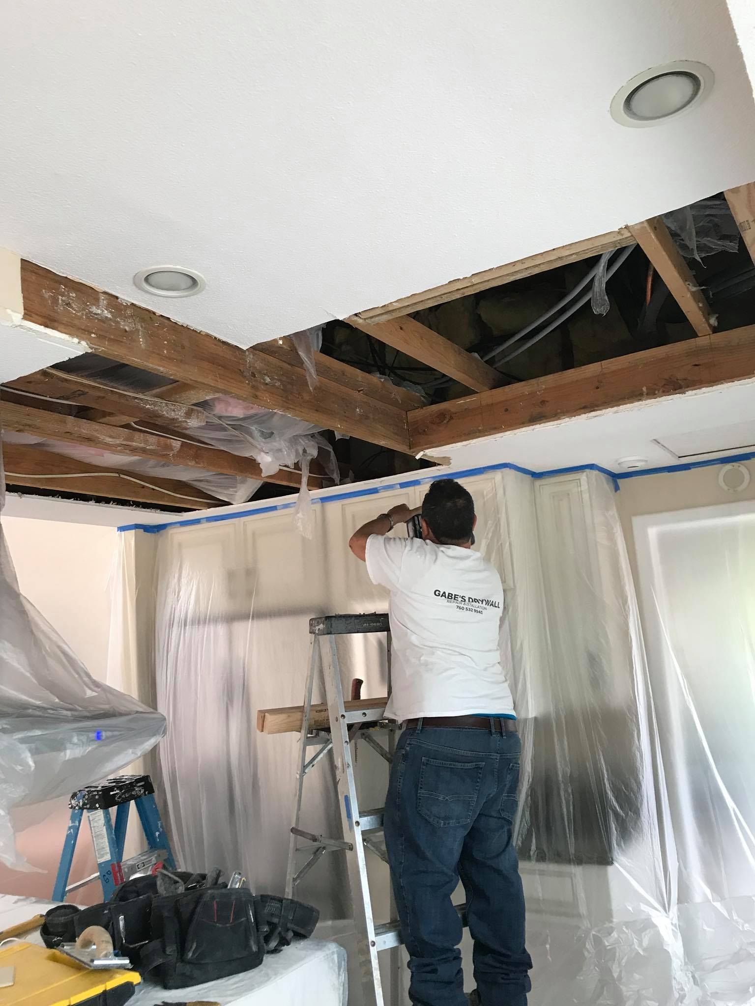 A man is standing on a ladder in a room.